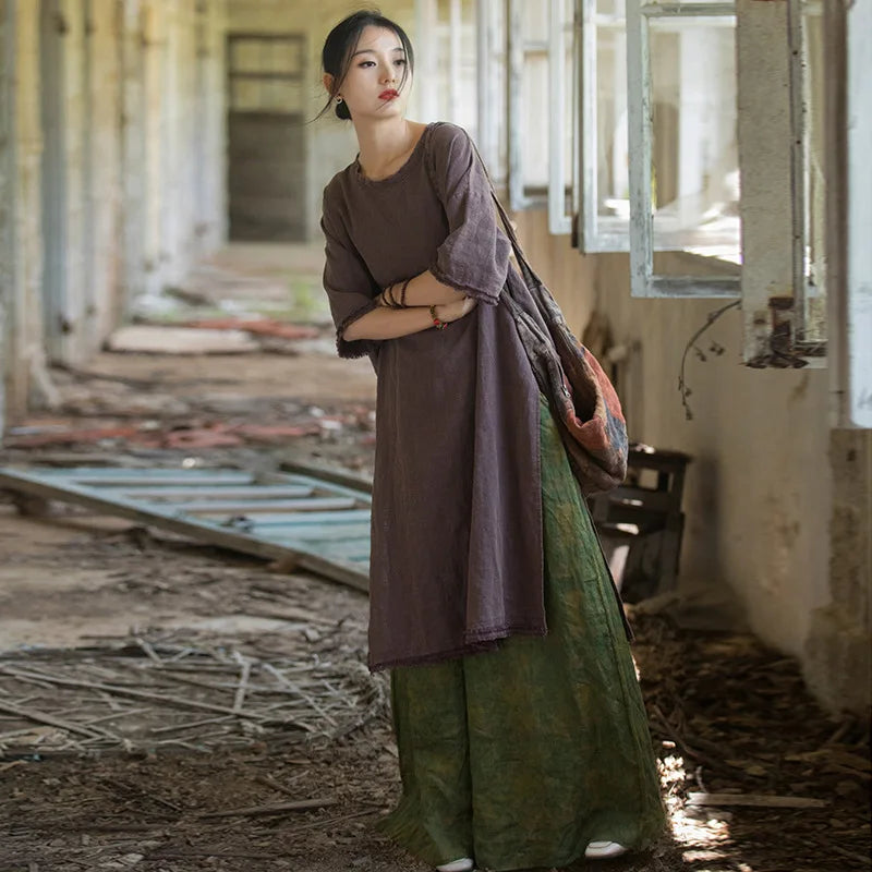 Woman in a long, dark dress standing in an abandoned building with debris on the floor.
