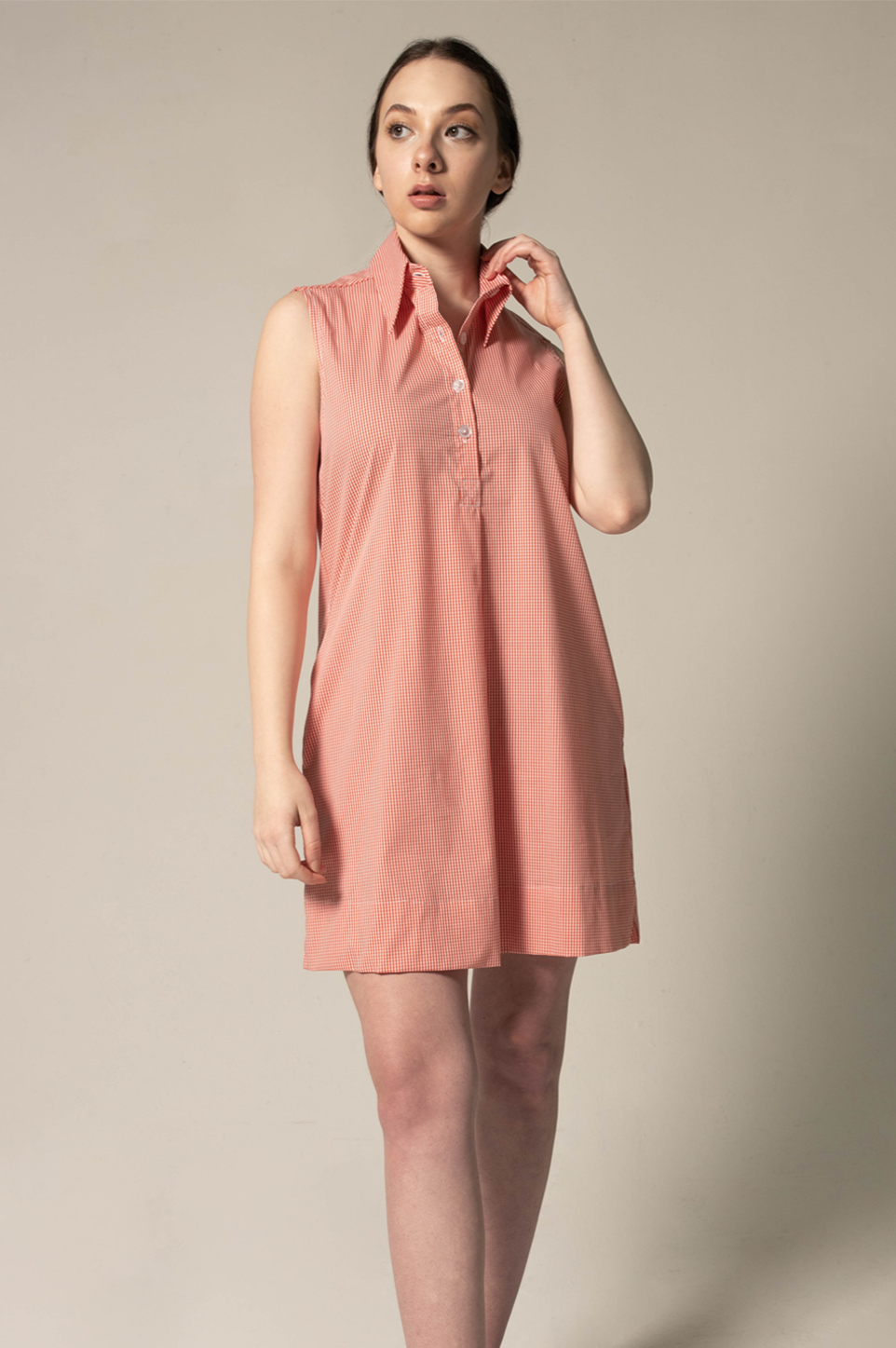 Woman wearing a pink sleeveless dress against a plain background