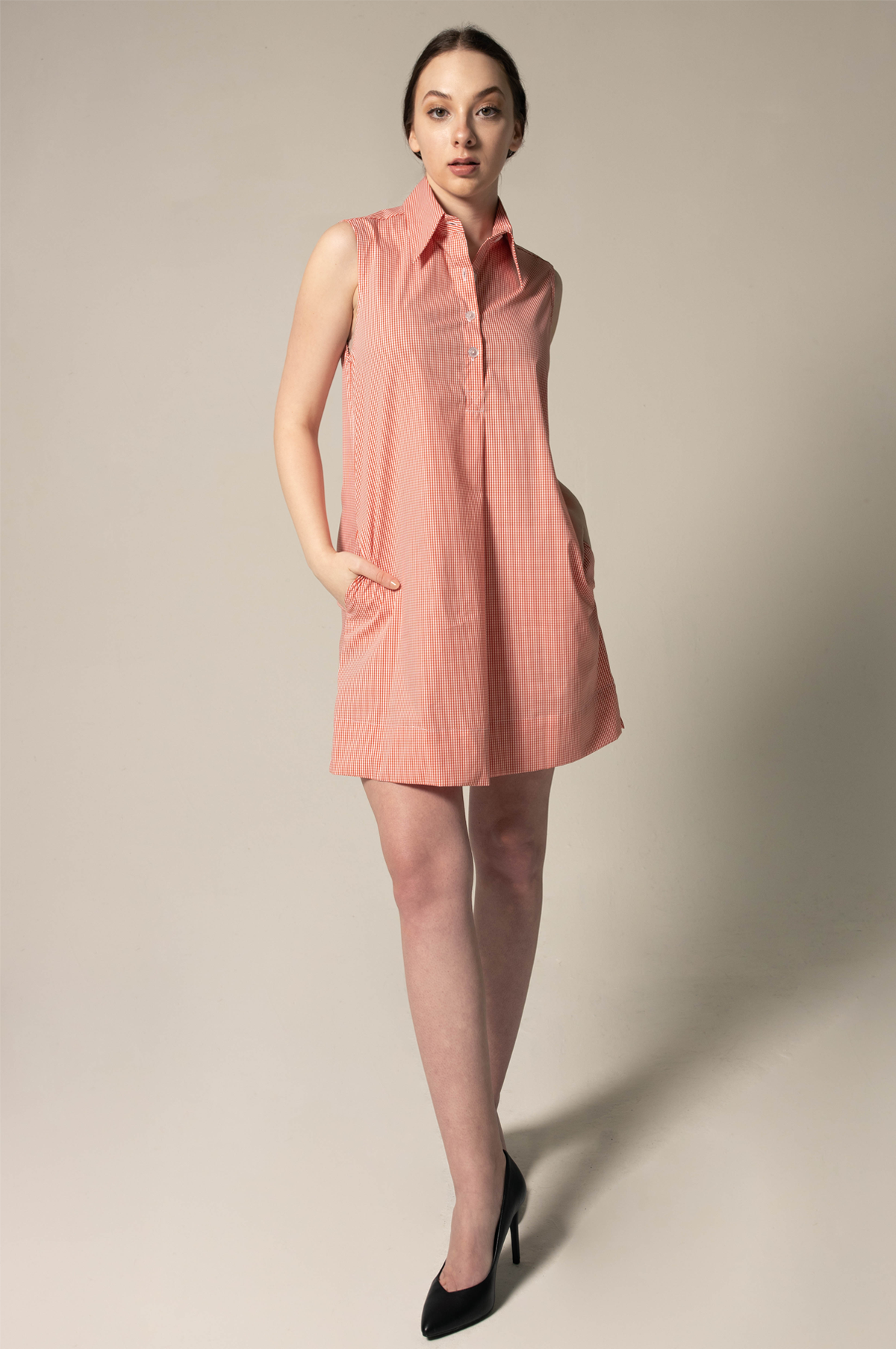 Woman wearing a sleeveless pink dress against a plain background