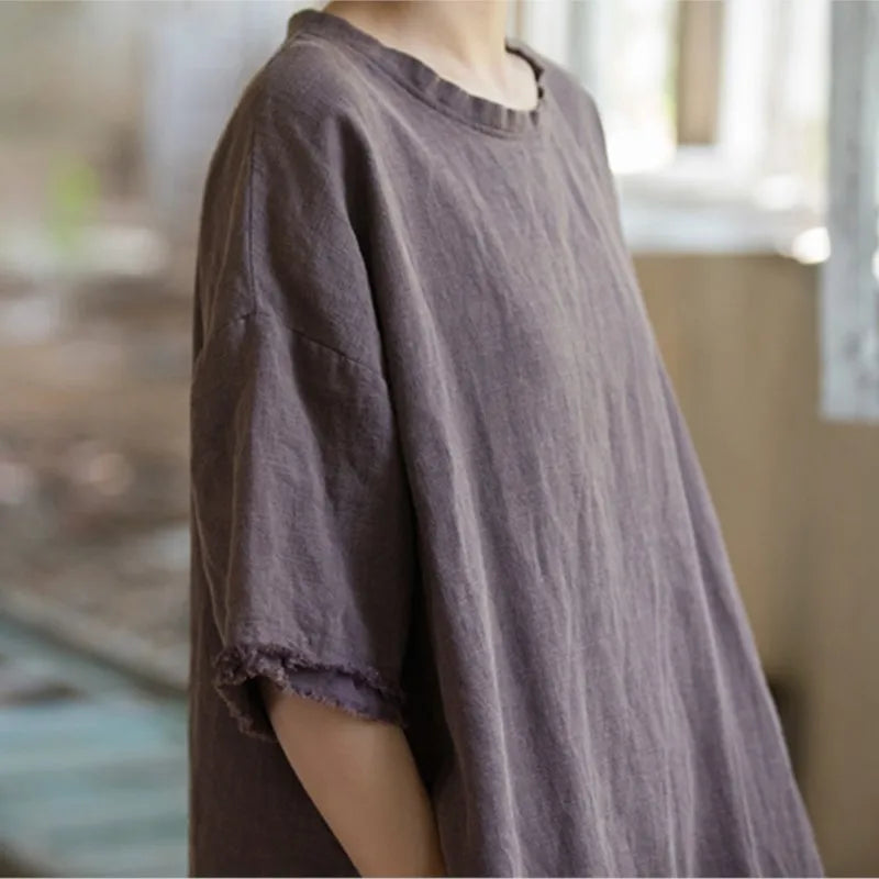 Person wearing a loose-fitting brown shirt in a blurred indoor setting