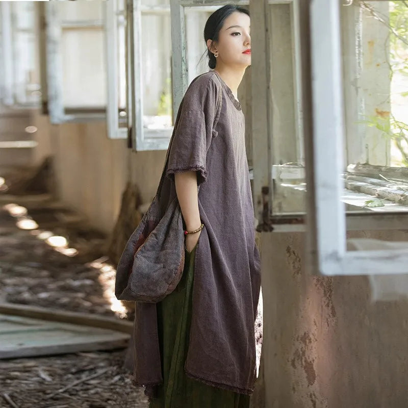 Woman in a long, dark dress standing in a sunlit room with large windows.