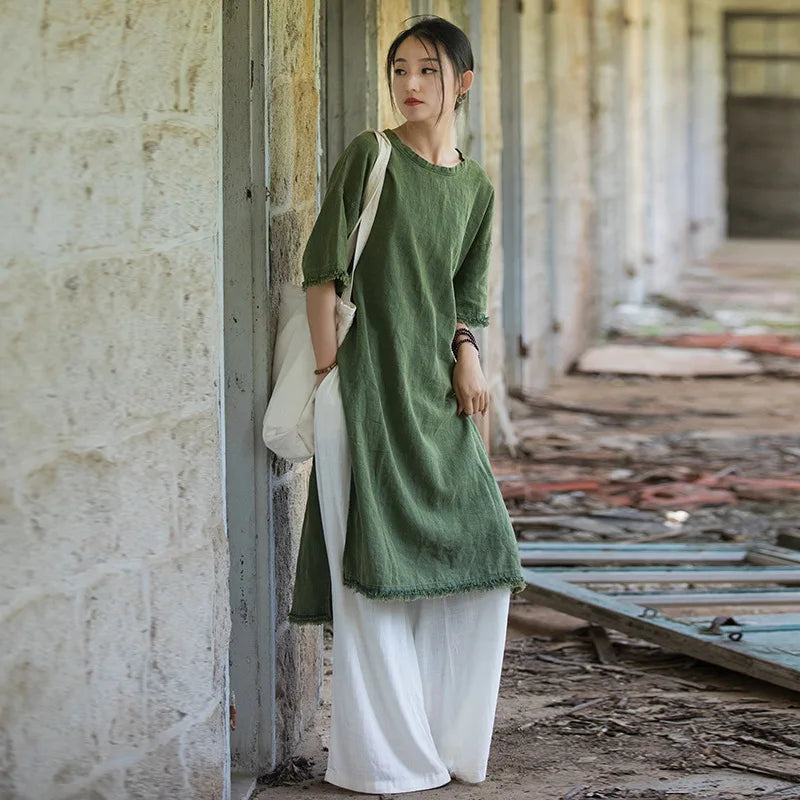 Woman in a green dress and white pants standing in an industrial setting.