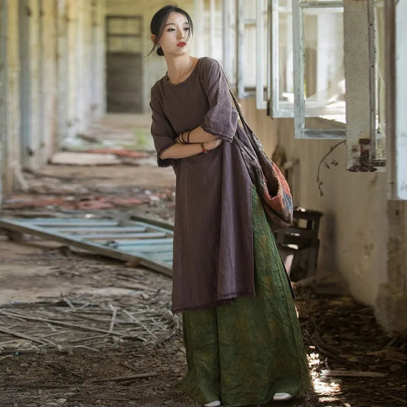 Woman in a long, dark dress standing in an abandoned building with debris on the floor.