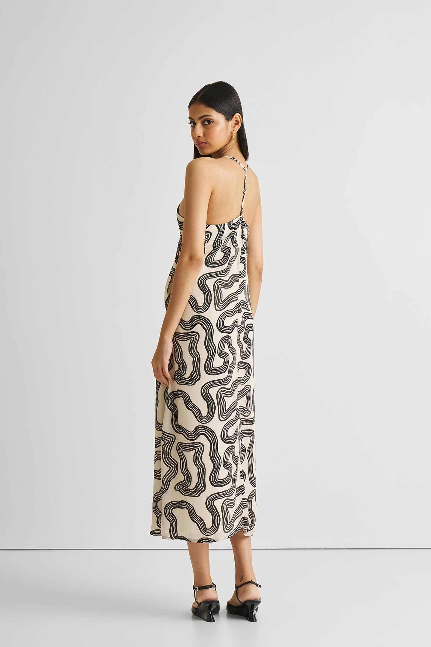 Woman wearing a patterned slip dress on a white background