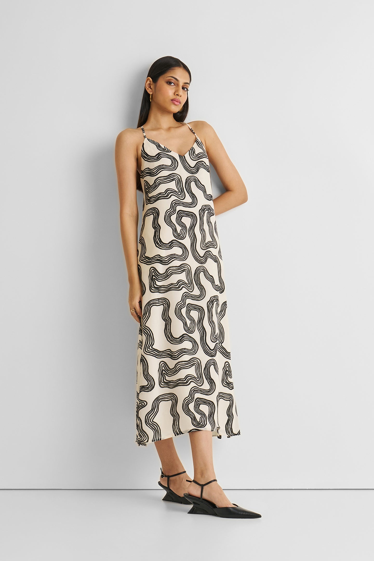Woman wearing a patterned slip dress against a white background