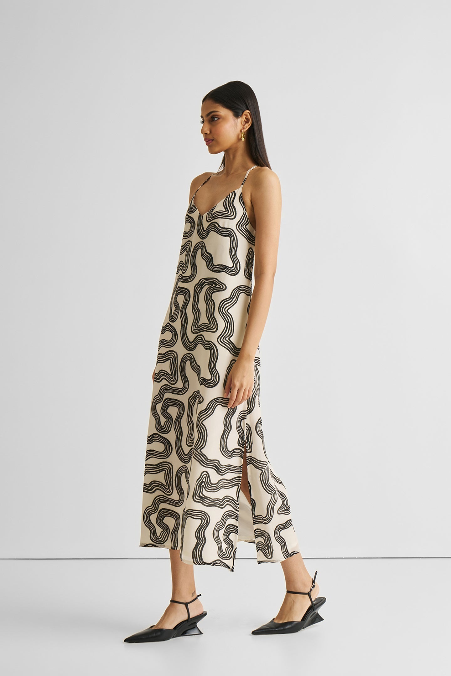Woman wearing a patterned slip dress on a white background