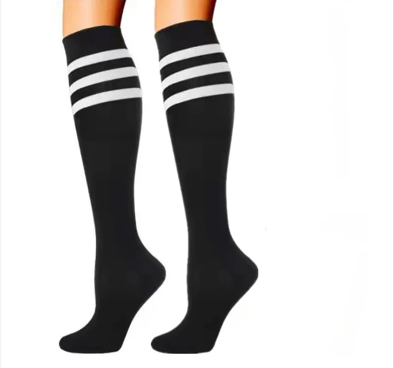 A pair of legs wearing Littles Collection Compression Socks Varicose Veins Medical Marathon—black knee-high with three white stripes—shown on a white background, designed for style and athletic performance.