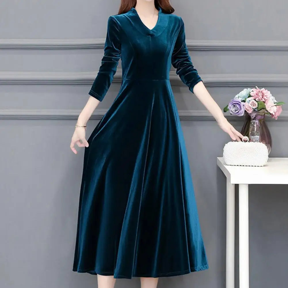 Woman wearing a teal velvet dress against a gray background