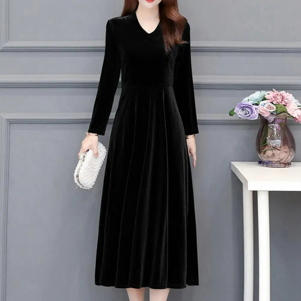 Woman wearing a black dress with long sleeves in an indoor setting.