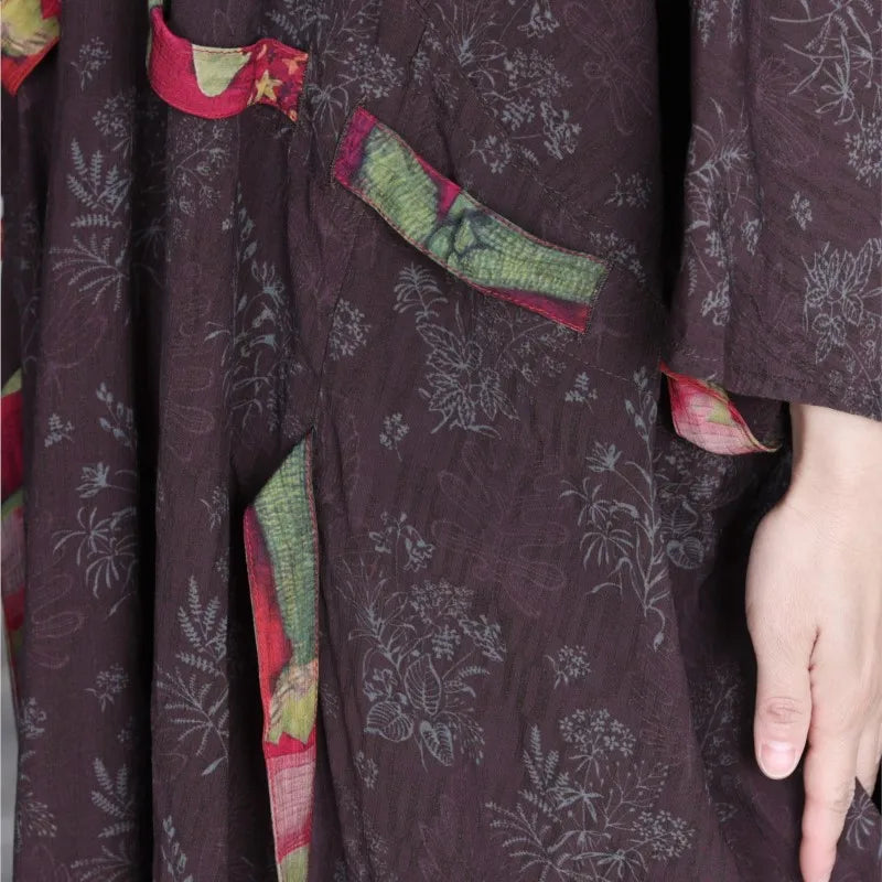 Close-up of a dark floral-patterned garment with colorful accents.
