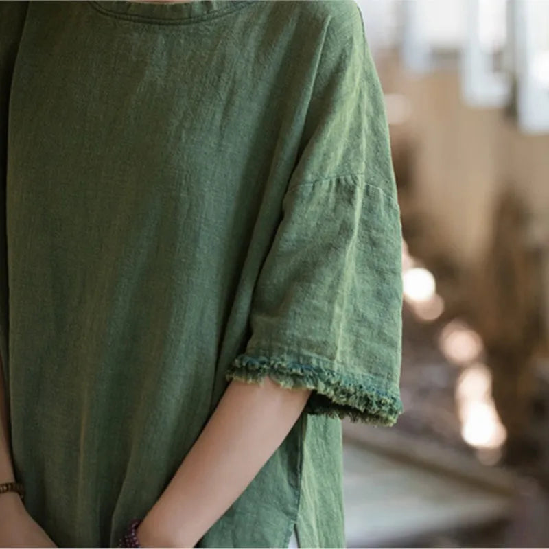 Green linen dress with ruffled sleeves worn by a person, blurred background
