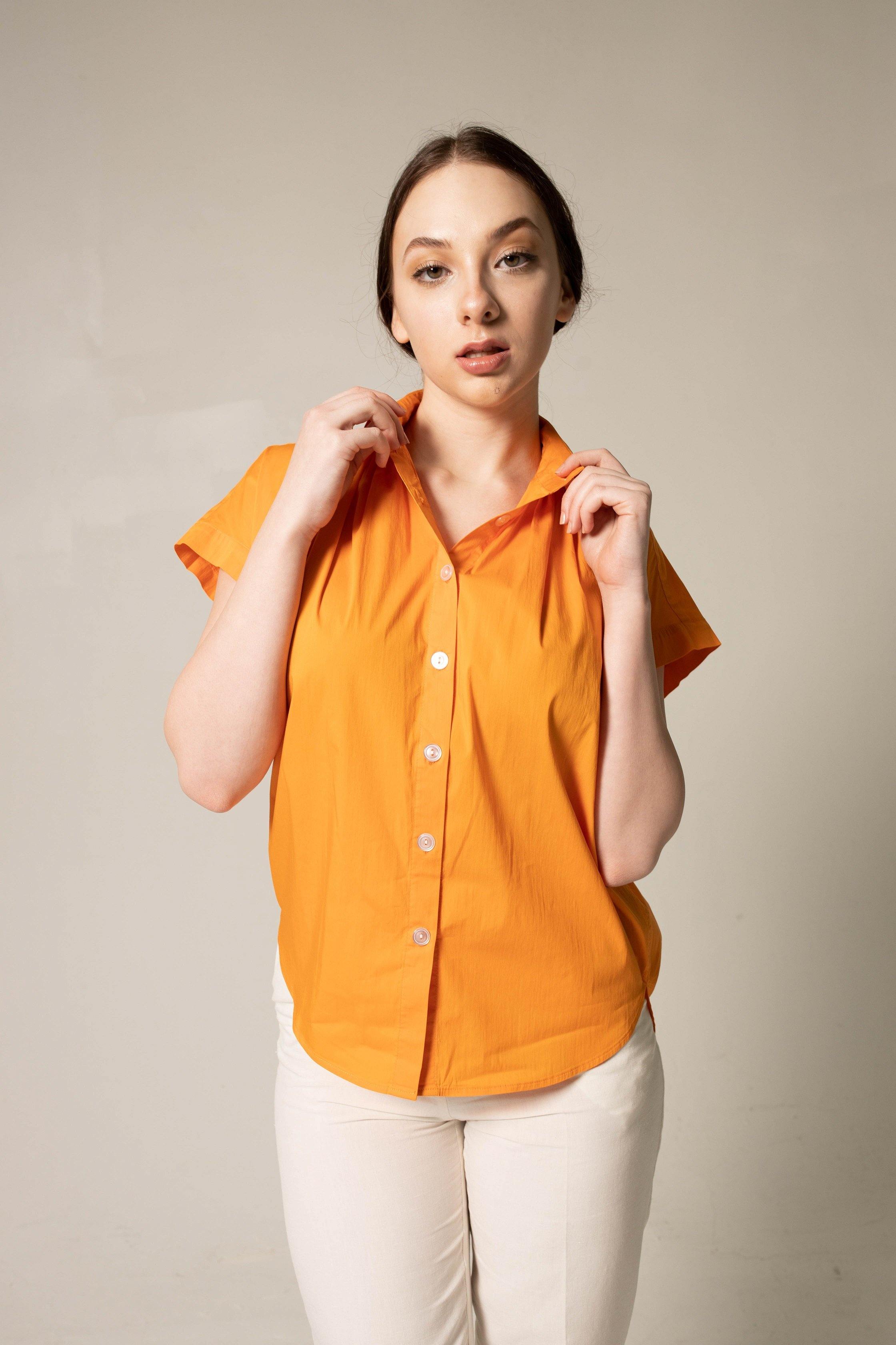 Woman wearing an orange shirt against a beige background