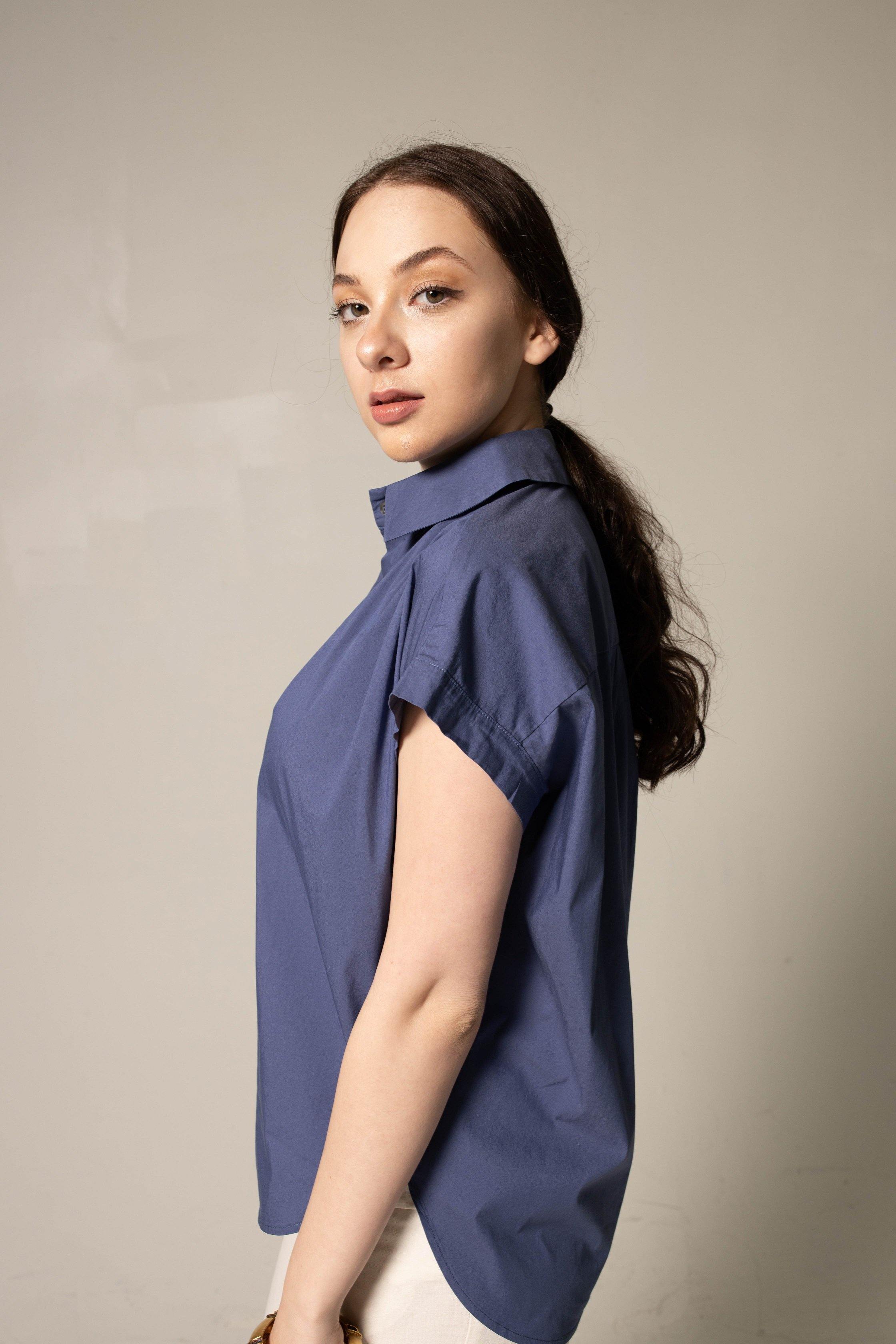 Woman wearing a blue sleeveless blouse against a beige background