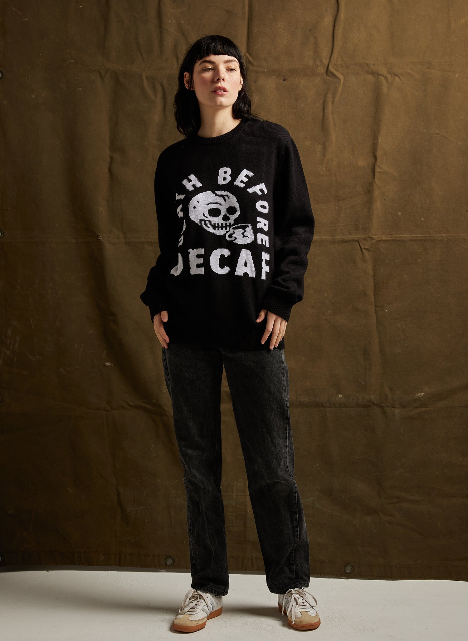 Person wearing a black sweatshirt with white text and graphics against a brown backdrop