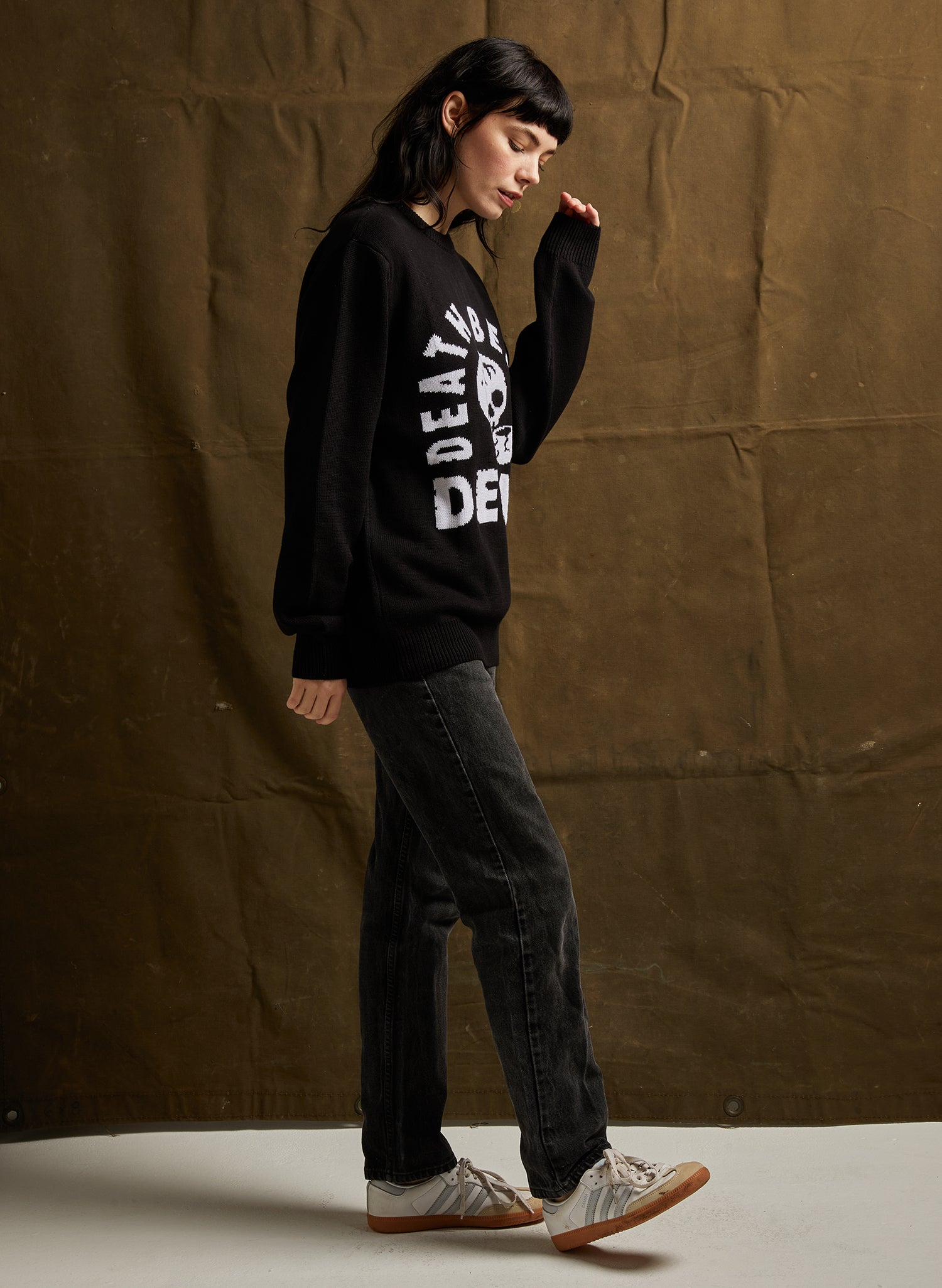 Person wearing a black sweatshirt with text against a brown backdrop