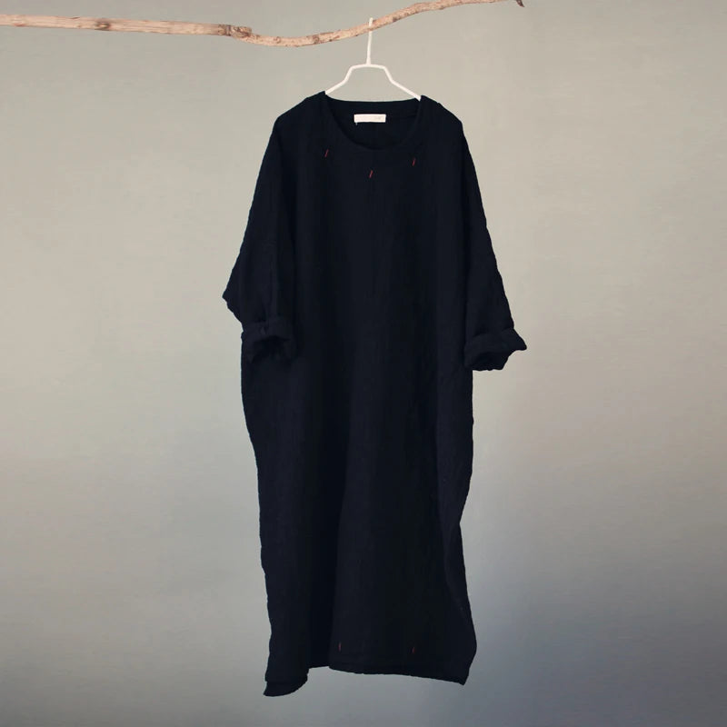 Black dress hanging on a hanger against a plain background
