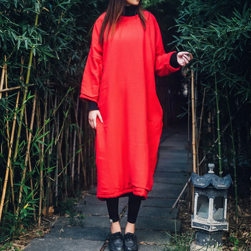 Person wearing a red dress standing in a garden with bamboo and lanterns.