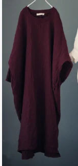 Long burgundy dress on a hanger against a dark background