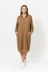 A woman wearing a brown sweater dress with pockets.