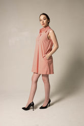 Woman wearing a pink sleeveless dress against a plain background
