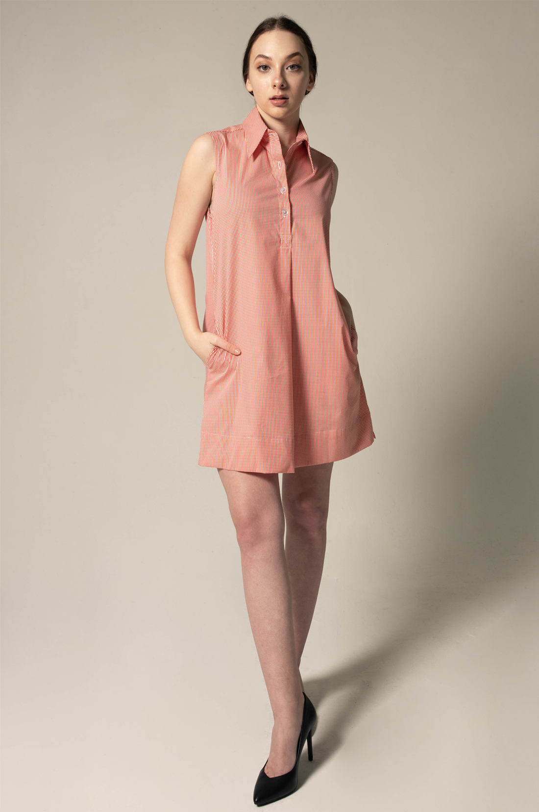 Woman wearing a sleeveless pink dress against a plain background
