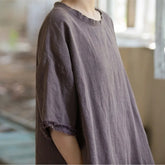 Person wearing a loose-fitting brown shirt in a blurred indoor setting