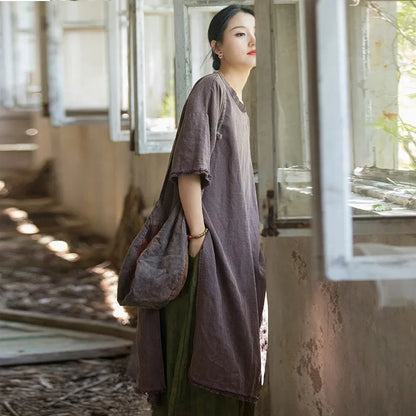 Woman in a long, dark dress standing in a sunlit room with large windows.