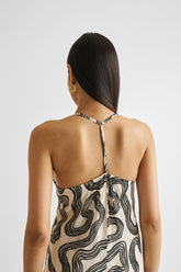 Woman wearing a sleeveless dress with a black and white pattern on a plain background