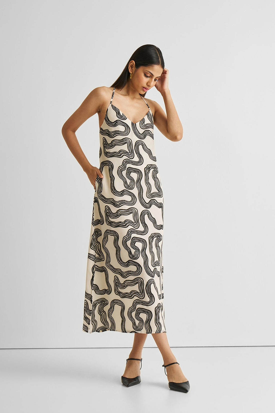 Woman wearing a patterned slip dress on a plain background