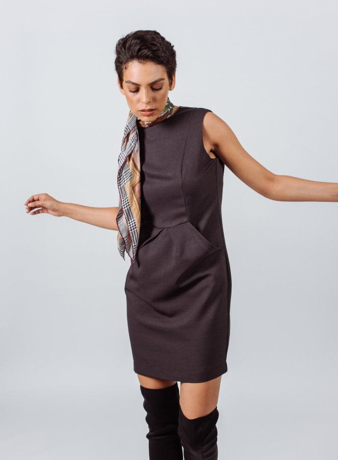 Woman wearing a dark brown sleeveless dress with a scarf on a light gray background