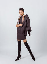 Woman wearing a brown dress and black knee-high boots on a white background