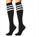 A pair of legs wearing Littles Collection Compression Socks Varicose Veins Medical Marathon—black knee-high with three white stripes—shown on a white background, designed for style and athletic performance.
