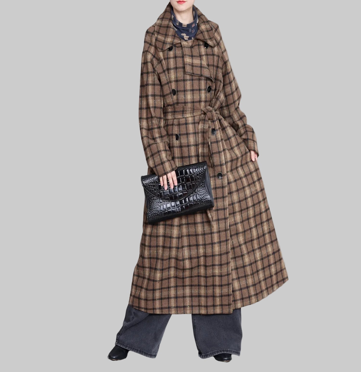 Person wearing a long plaid coat holding a black handbag against a gray background with decorative elements.
