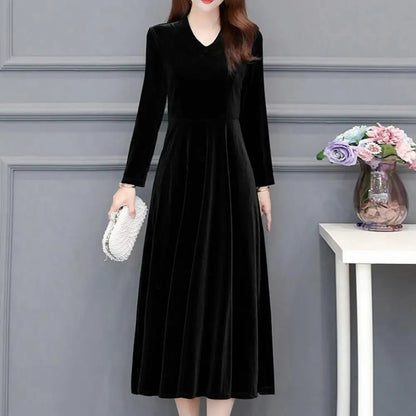 Woman wearing a black dress with long sleeves in an indoor setting.