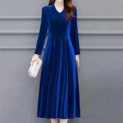 Woman wearing a blue velvet dress against a gray background