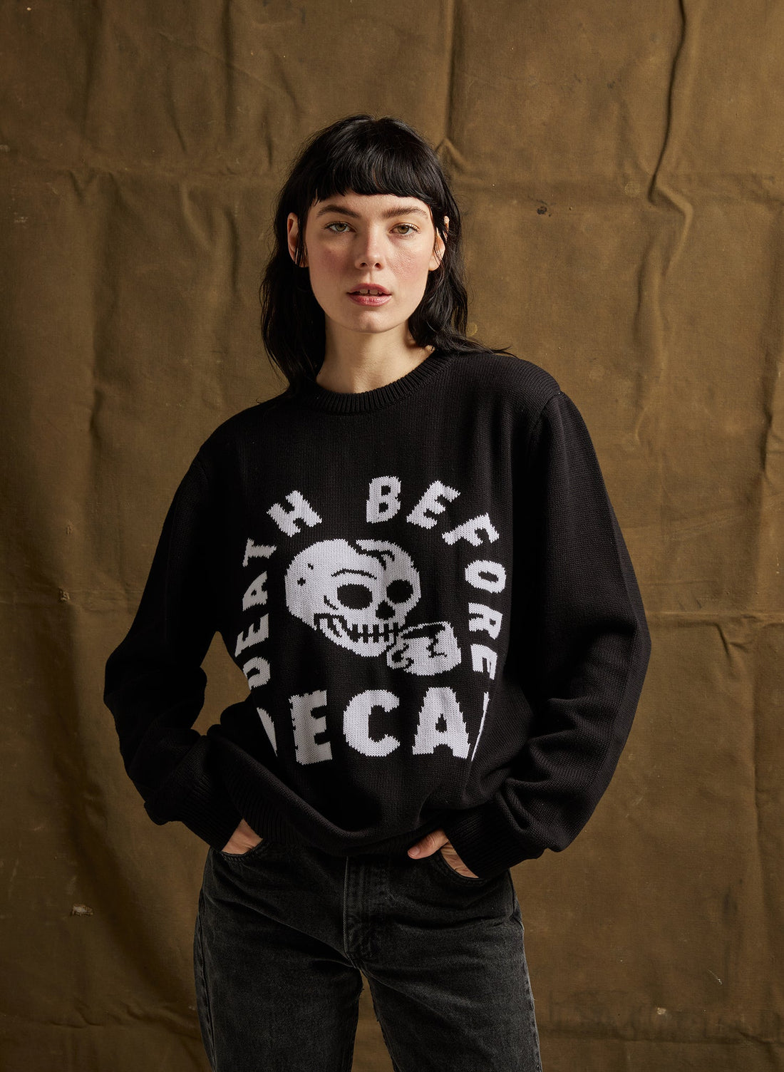 Person wearing a black sweatshirt with a graphic design against a brown background