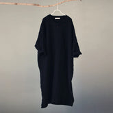 Black dress hanging on a hanger against a plain background