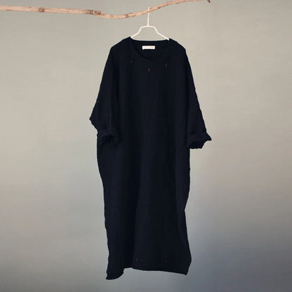 Black dress hanging on a hanger against a plain background