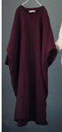 Long burgundy dress on a hanger against a dark background