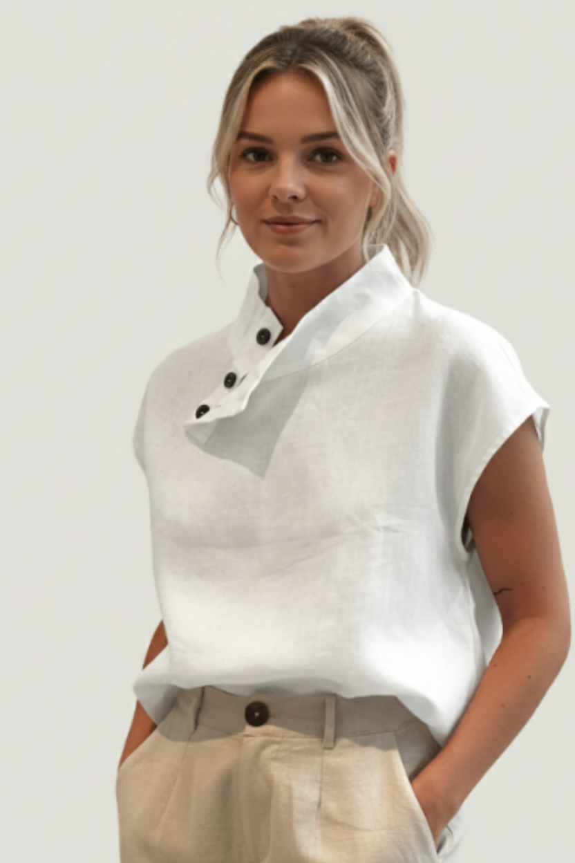 Woman wearing a white sleeveless top with a gray accent and beige pants on a plain background