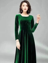 Woman wearing a green velvet dress against a gray background